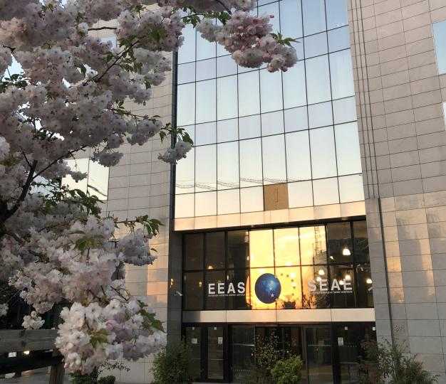 he entrance of the European External Action Service building at sunset, with a tree in bloom in front of it
