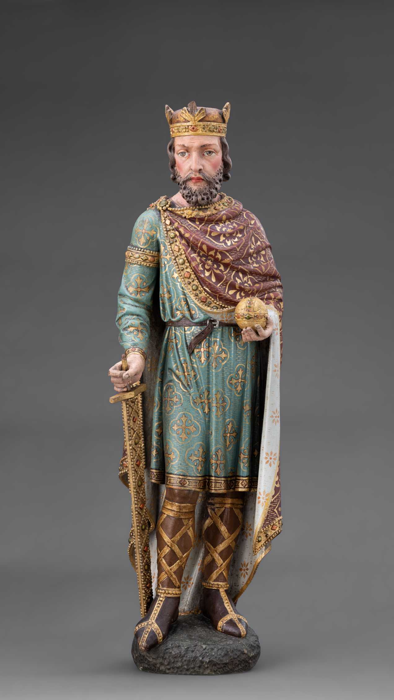 Wooden painted statue of a bearded king in ornate robes, holding a scepter and orb, with a crown on his head.
