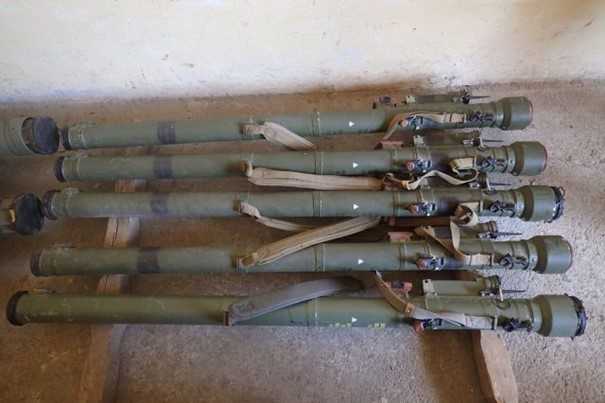 Picture of five granade launchers lying on the floor next to each other.