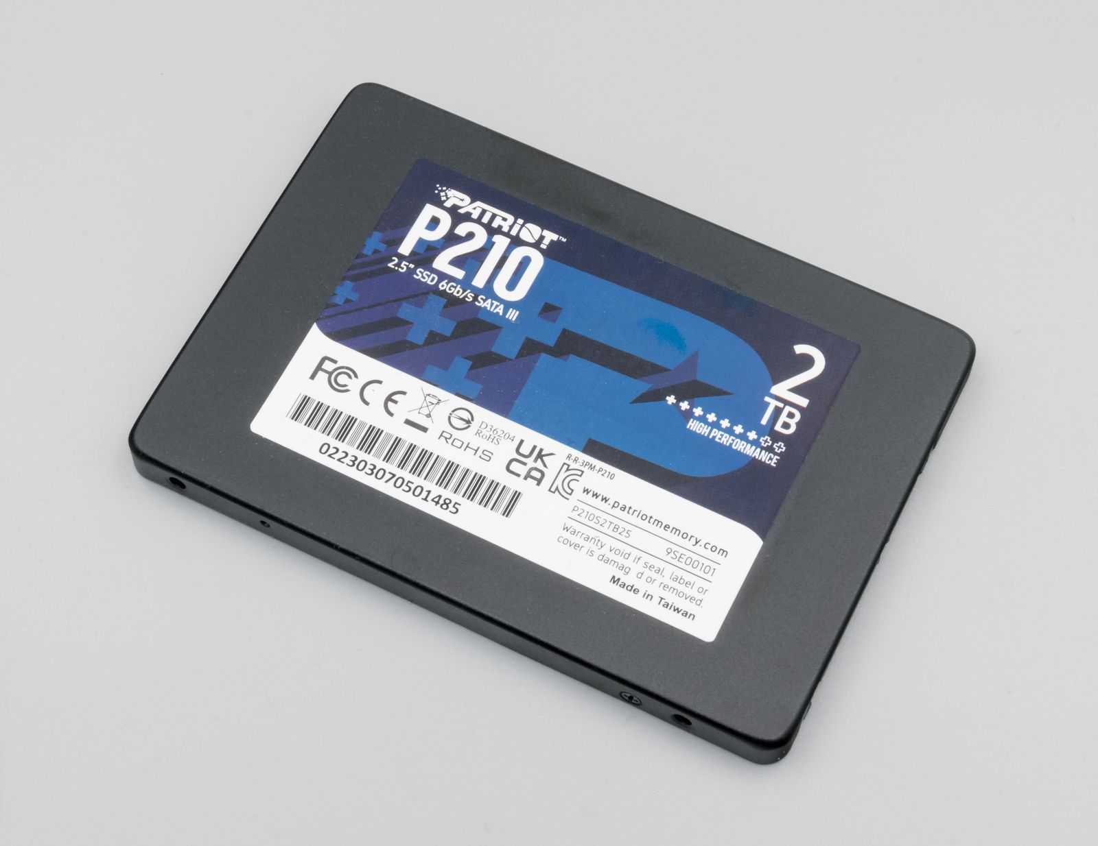 A black SSD with a label that says ‘2 TB’, the (illegible) name of the manufacturer, the type designation P210 and a barcode.