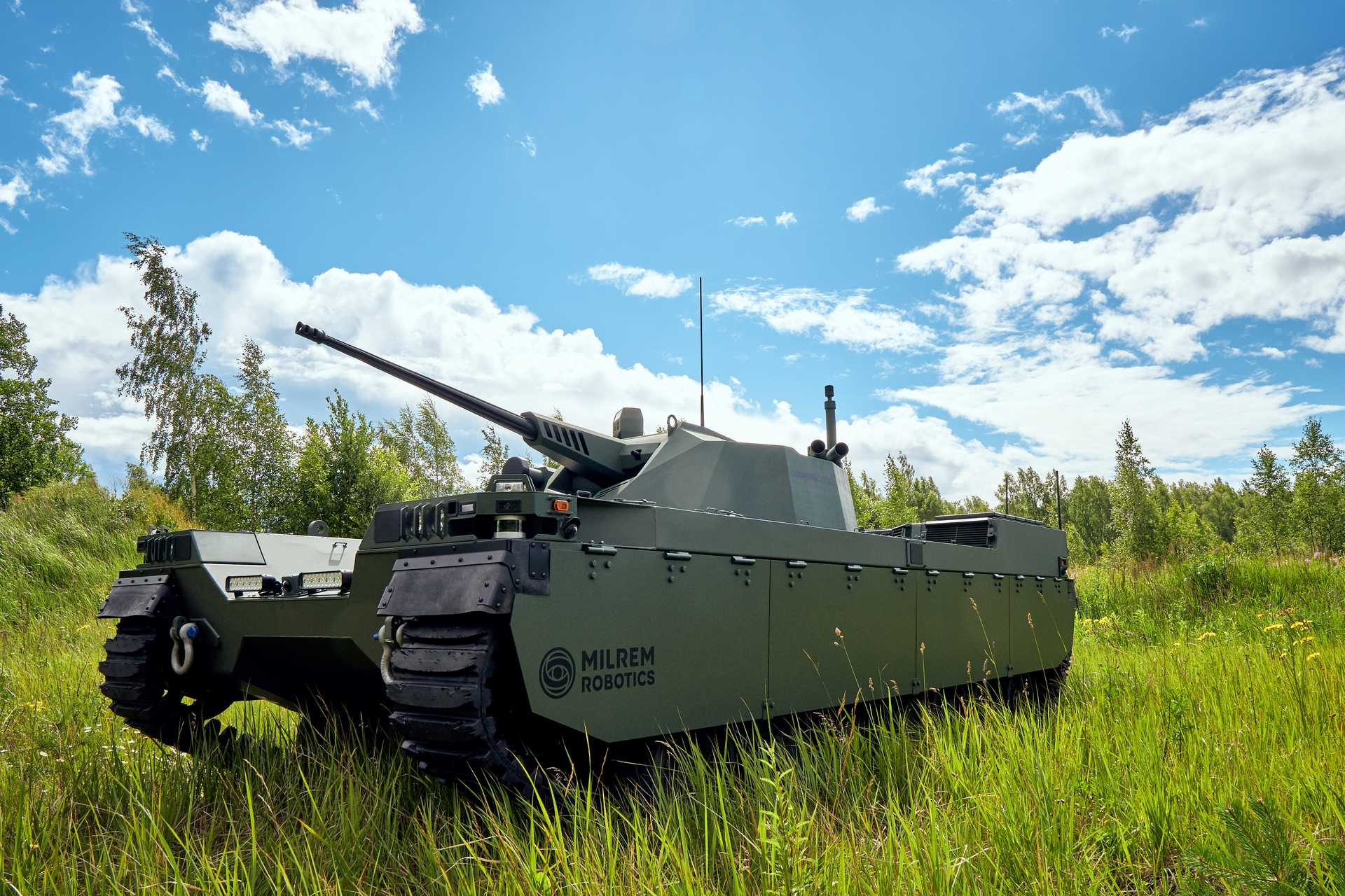 TA tank with a small cannon and the inscription ‘Milram Robotics’ in a meadow with tall grass. Small trees can be seen in the background.