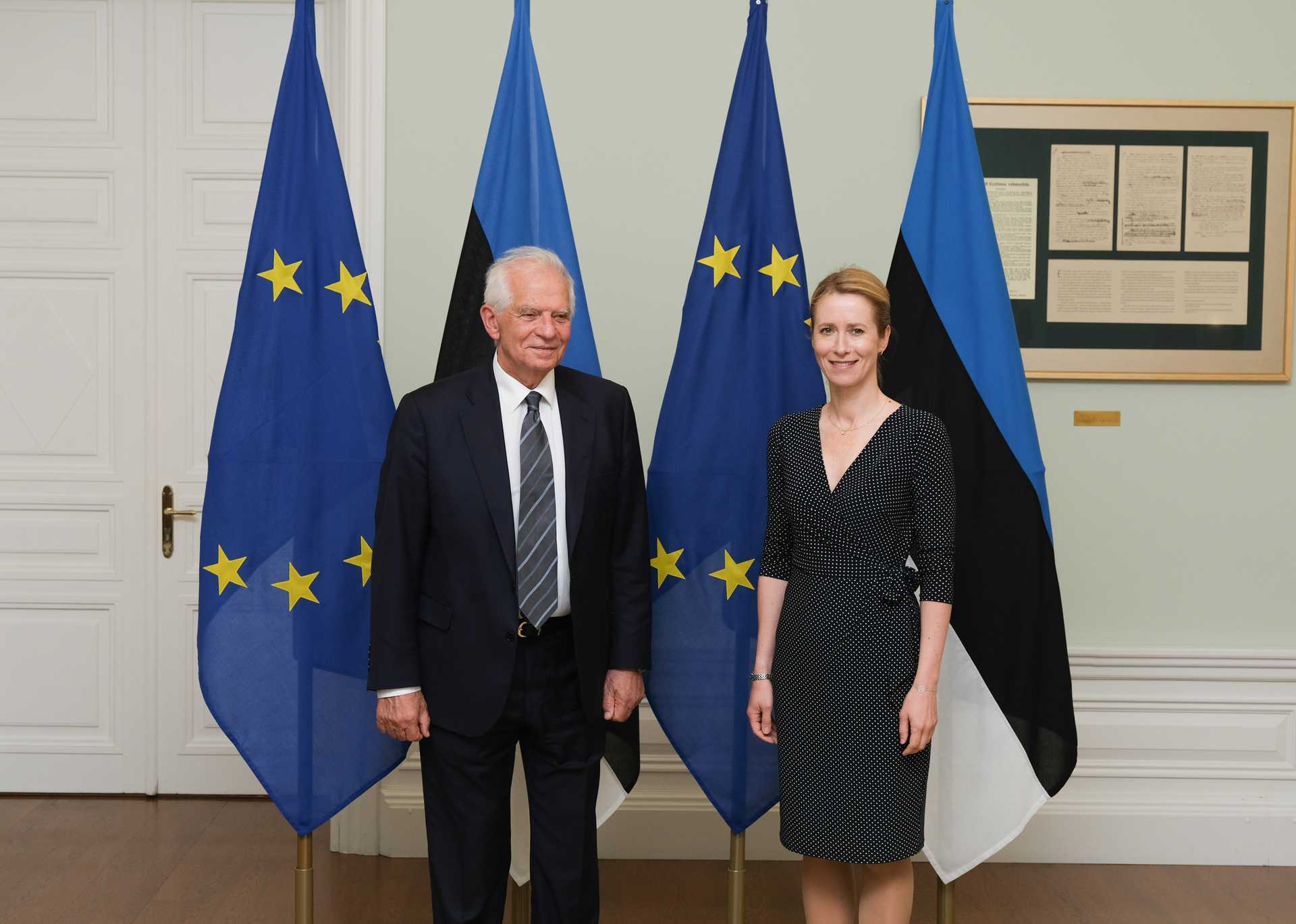 Kaja Kallas (r) with her predecessor, Josep Borrell standing in front of two EU and two Estonian flags, looking into the camera
