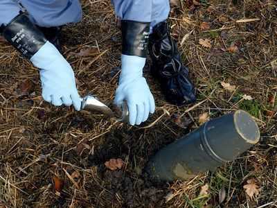 Picture of two hands in gloves taking soil samples.
