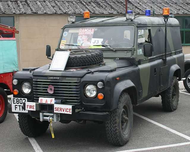 Picture of a Land-Rover in camouflage and a sign saying 'AF Fire Service' standing at parking lot.