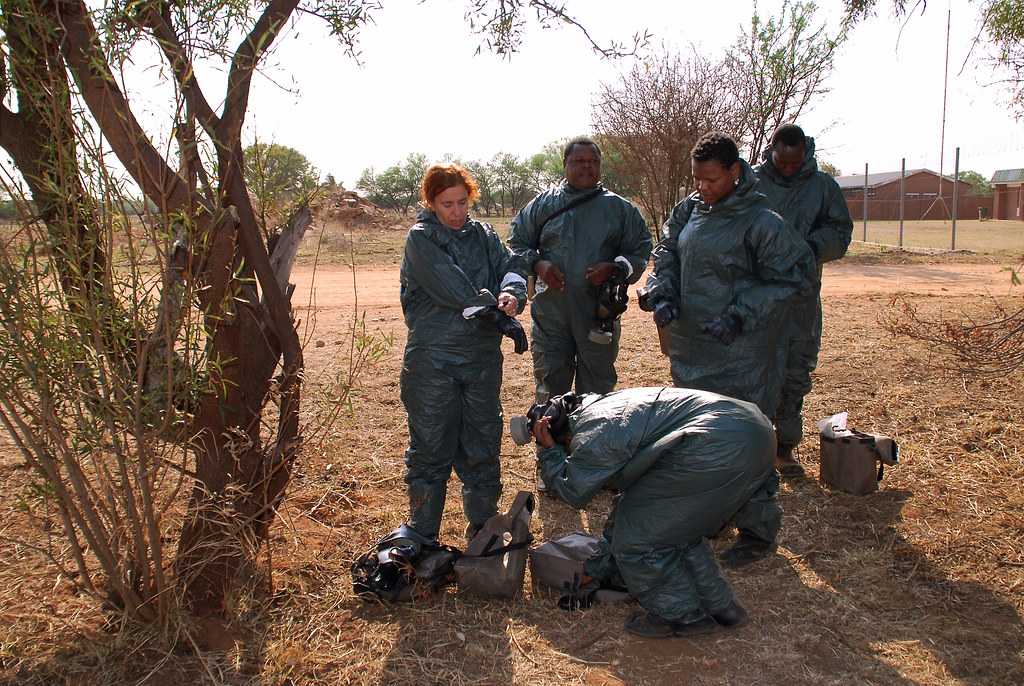 Five people in protective gear standing in a rather dry environment.