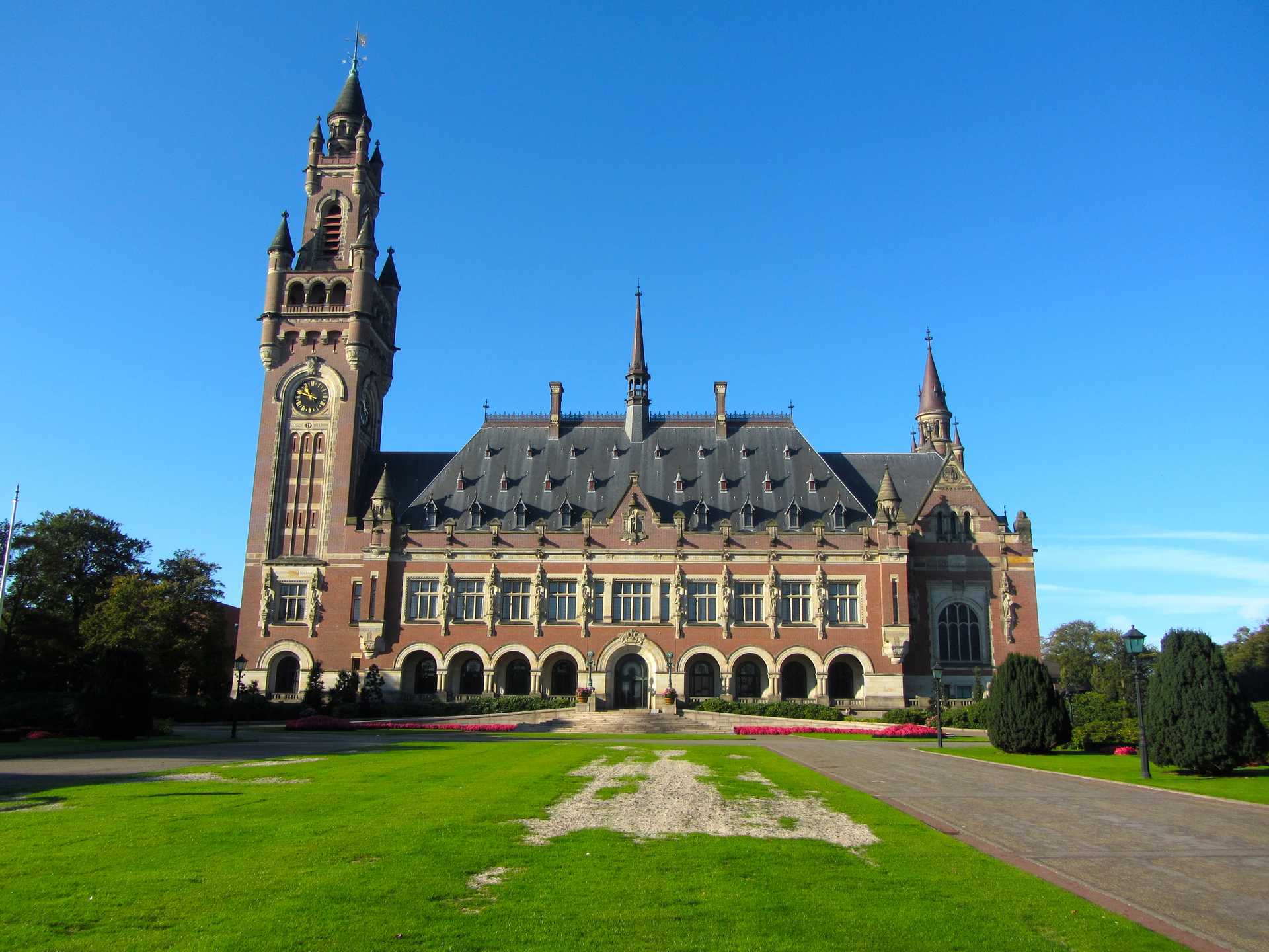 The International Court of Justice is located in an impressive historic building with a clocktower and surrounded by gardens.