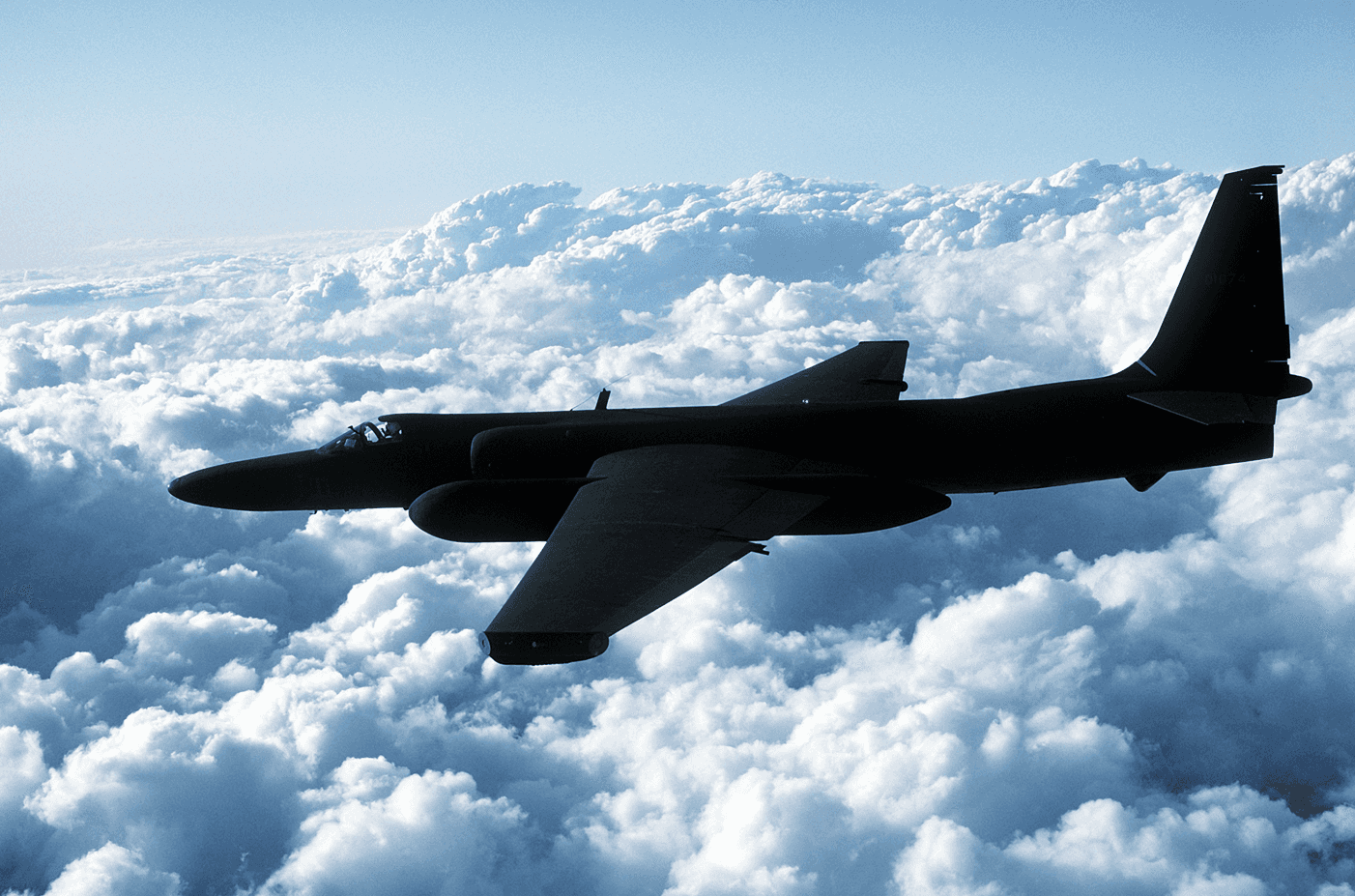 Military airplane flying above clouds.