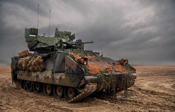 Muddy tank standing on mud in front of dark clouds.