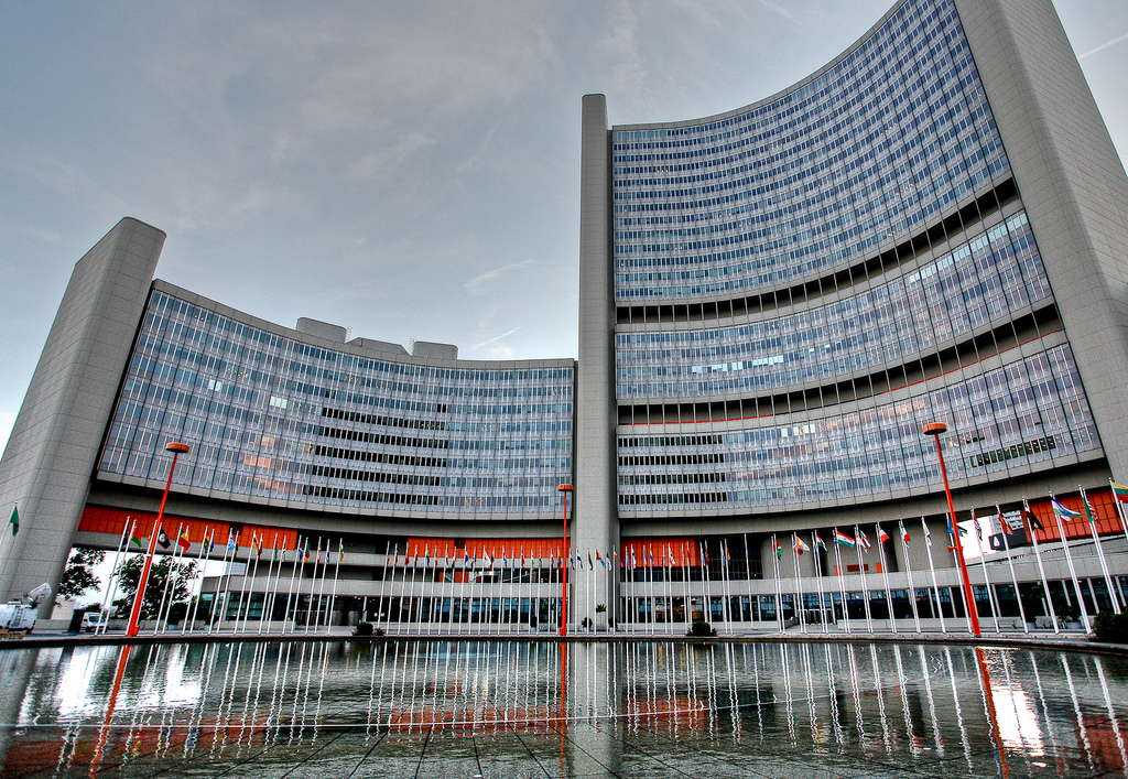 The photograph shows a huge building with several Nationflags up front. The Building is IAEA quarter office in Vienna.